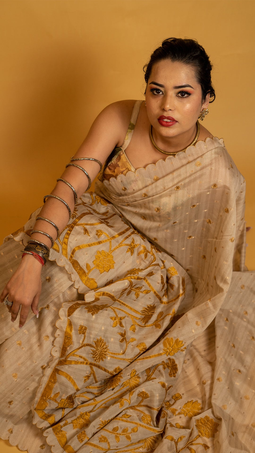 Beige tissue silk saree with golden floral embroidery and scalloped designer border